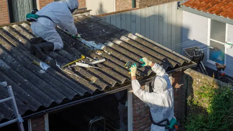 Roofers in protective gear repairing a damaged roof