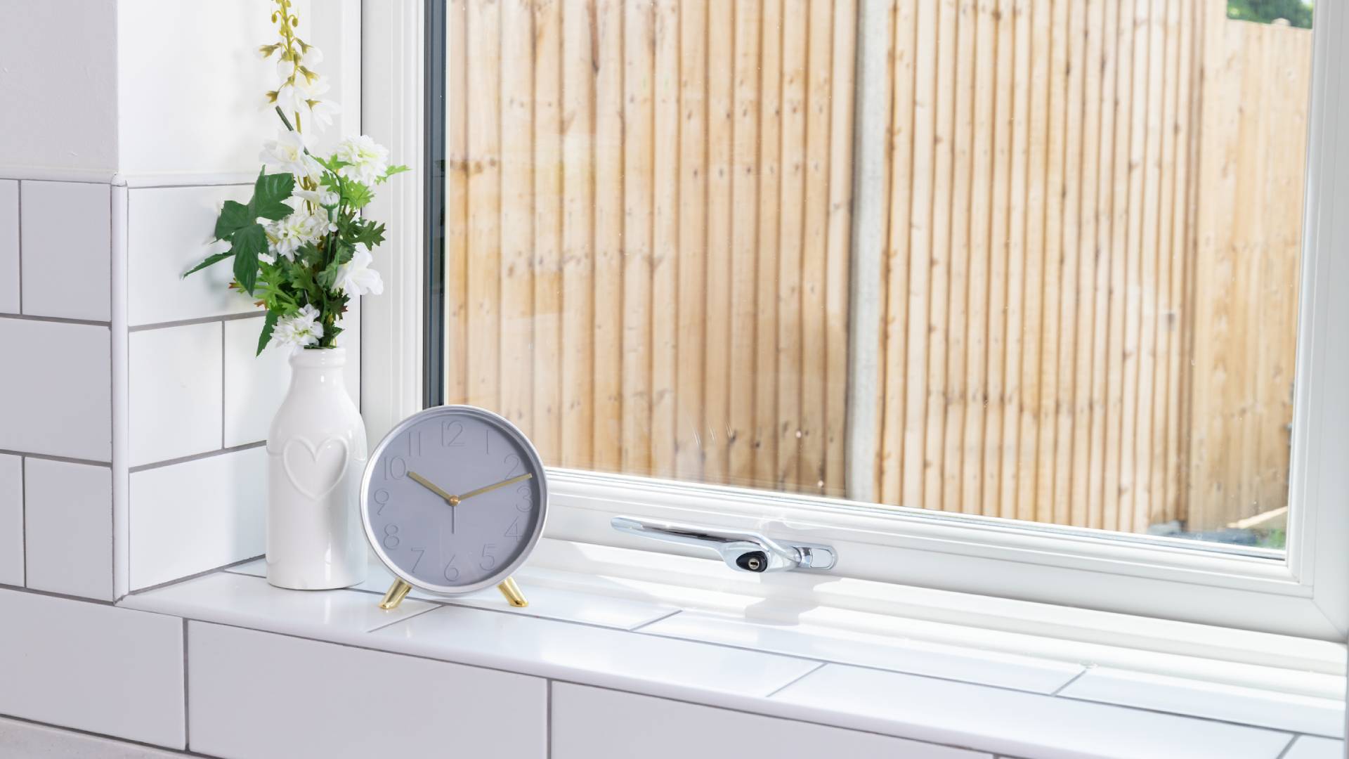 White window with gray clock and white flowers