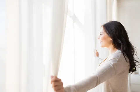 Woman opening a window and looking out