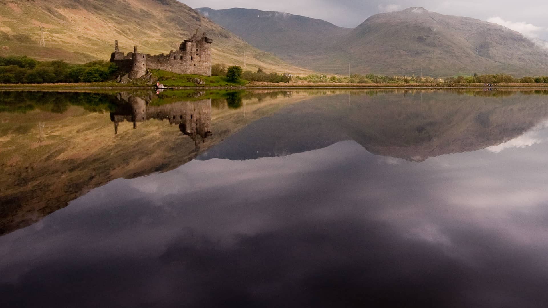 Ruined castle reflected in calm lake water