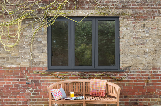 Dark gray Everest conservatory window with brick wall and wooden bench