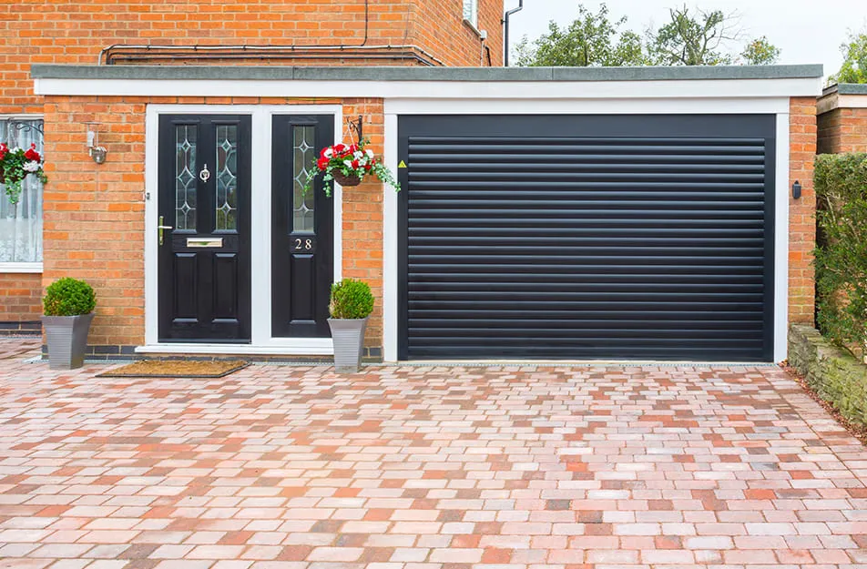 Black garage door with brick driveway