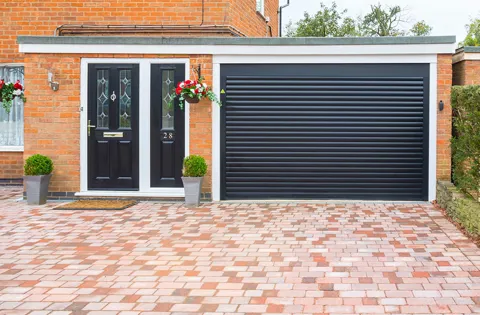 Black garage door with brick driveway