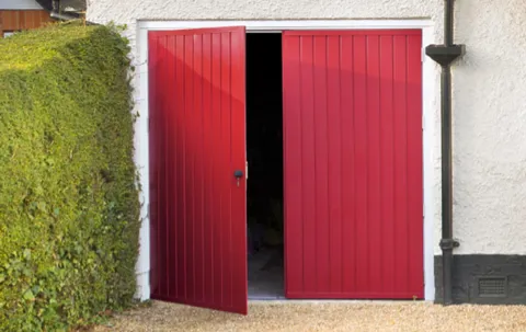 Red garage doors open to garage interior