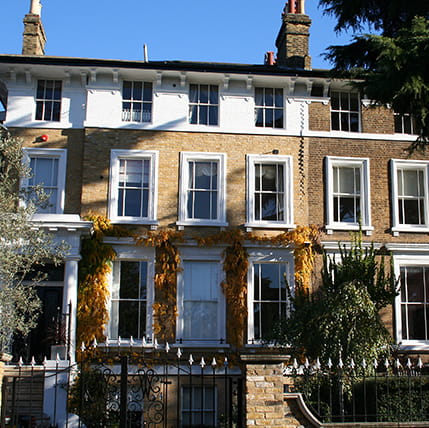 Traditional terraced house with white windows and autumn foliage