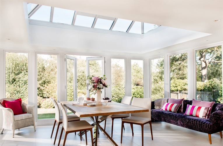 White Everest conservatory with large windows and wooden table