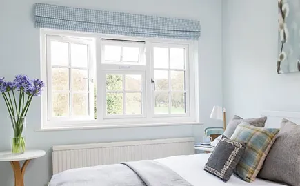 Light blue room with white window and light gray bed